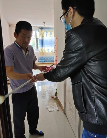 图为辅具站工作人员为视力残疾人送去盲杖