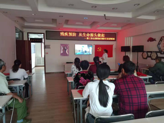 图为石人镇专职委员陈红在为大家播放残疾预防宣传片